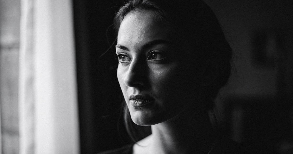 Portrait noir et blanc d une femme pres d une fenetre avec lumiere laterale